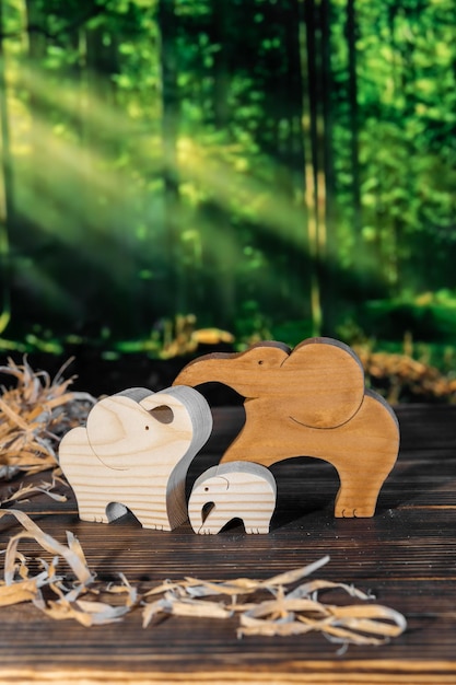 Wooden puzzle in the form of a family of handmade elephants on the background of the forest