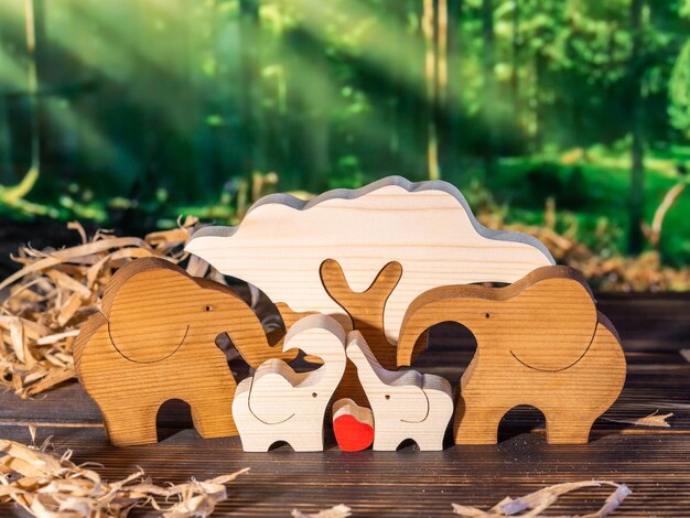 Wooden puzzle in the form of a family of handmade elephants on the background of the forest