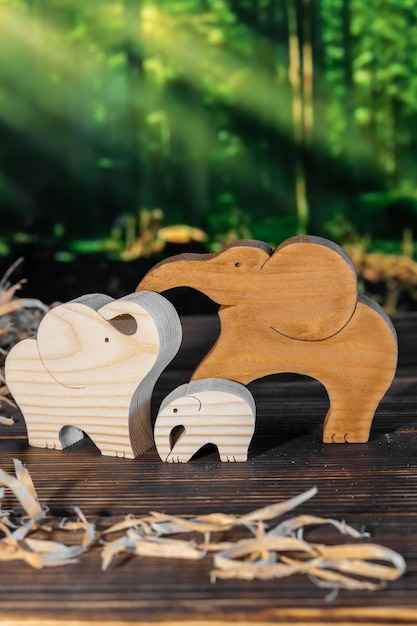 Wooden puzzle in the form of a family of handmade elephants on the background of the forest