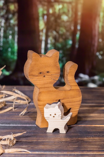 Wooden puzzle in the form of a handmade cat family on the background of the forest