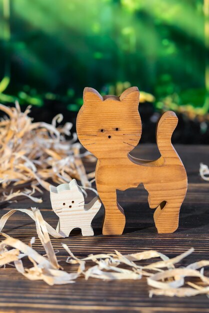 Wooden puzzle in the form of a handmade cat family on the background of the forest