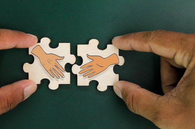 wooden puzzle with two shaking hands icons the concept of deal or agreement Business partner