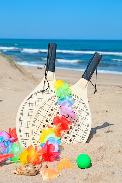 Photo wooden rackets and hawaiian necklace at the beach