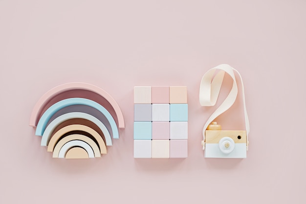 Wooden rainbow, colorful blocks and toy camera. Stylish baby toys on pastel pink background. Eco friendly, plastic free toys accessories for kids. Flat lay, top view