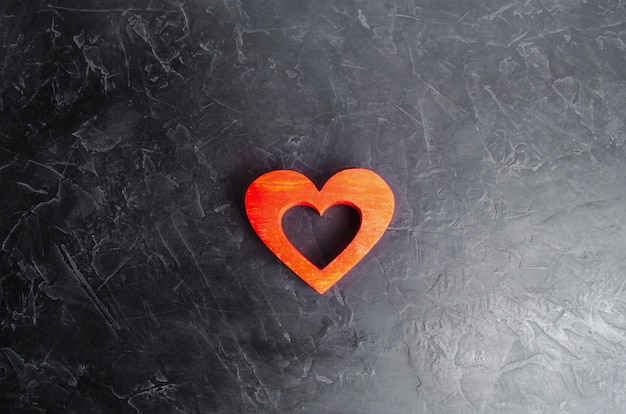 Wooden red heart on a gray concrete background. 