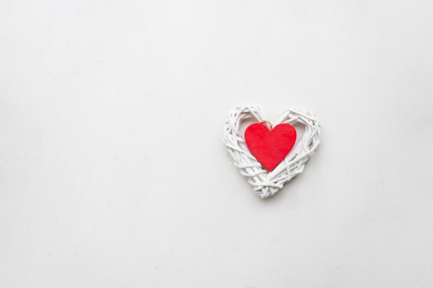 Wooden red heart on a white wall. love and romance. Heart shape. The relationship between lovers. Minimalism.