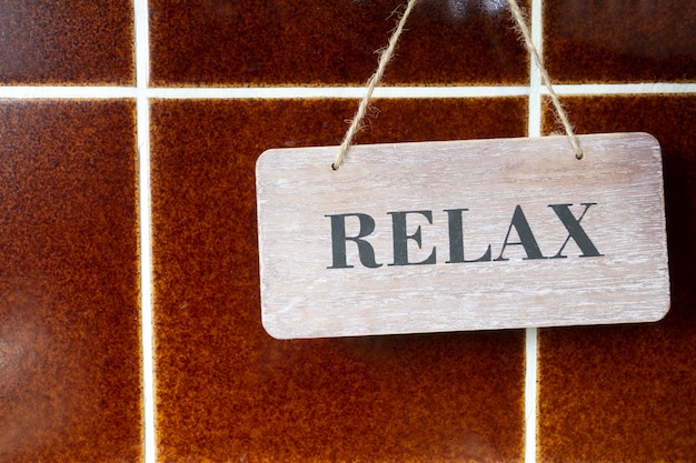 A Wooden Relax Sign on a brown tiled Wall, retro design wall texture