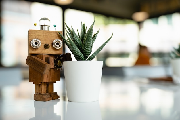 Wooden robot with cactus on white table