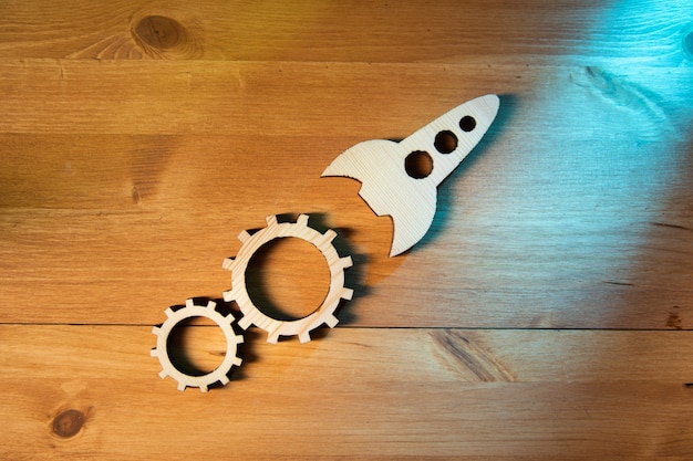 Wooden rocket with gears on the wooden background