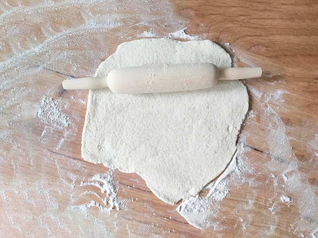 Photo wooden rolling pin and dough on wooden table