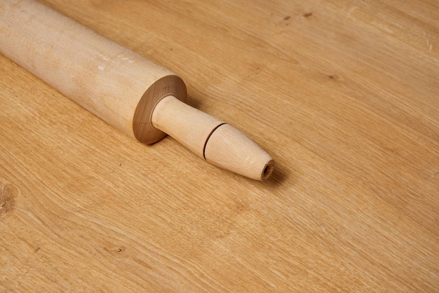 A wooden rolling pin is laying on a table.