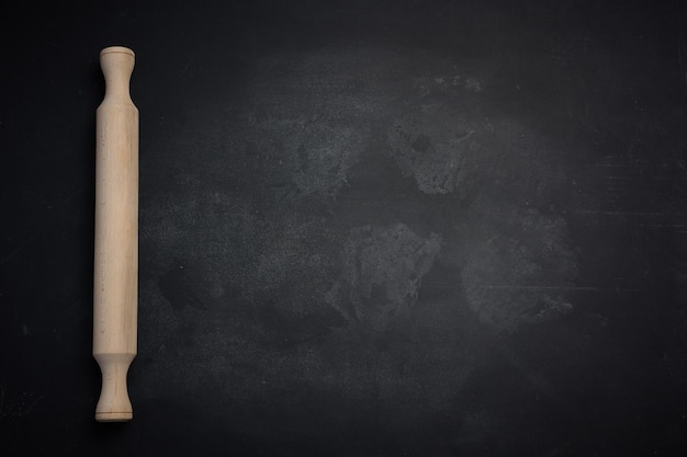 Wooden rolling pin for rolling dough on a black background top view Copy space