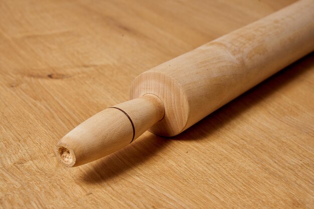 A wooden rolling pin sits on a table next to a wooden table.