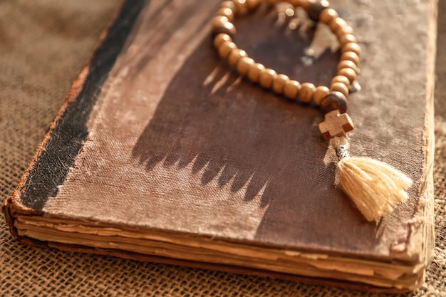 Wooden rosary beads and old book on sackcloth