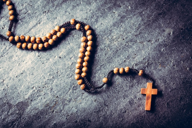 Wooden rosary laying on stone background