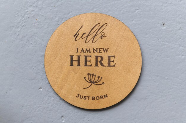 Wooden round board with the inscription I am new here on a gray background