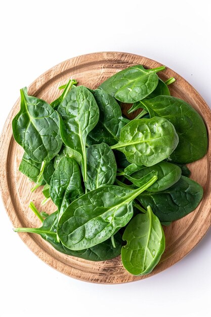 Photo wooden round plate with fresh spinach leaves top view