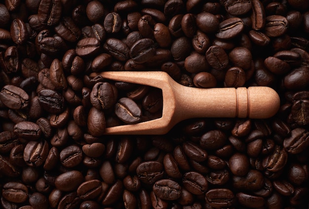 Wooden scoop on coffee beans background