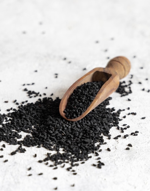 Wooden scoop of Indian spice Black cumin nigella sativa or kalonji seeds close up