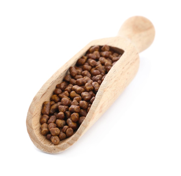 Wooden scoop with buckwheat tea granules on white background