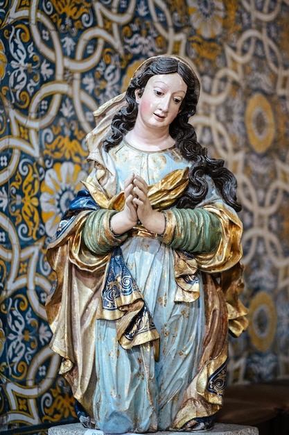 Wooden sculpture of the Virgin Mary against the background of azulejo tiles