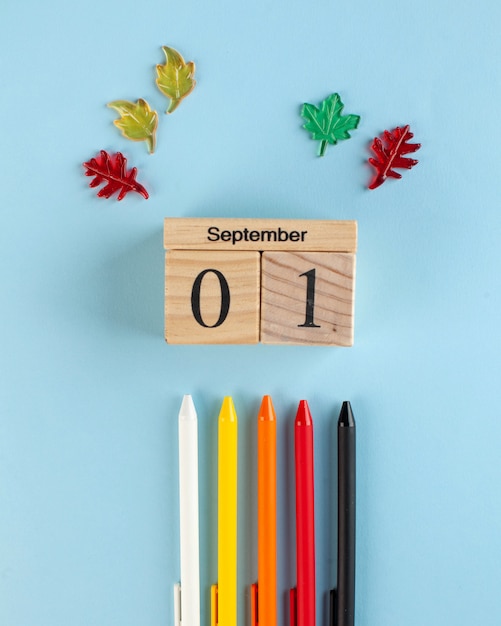 Foto calendario 1 settembre in legno, penne colorate su sfondo blu. inizio dell'anno scolastico