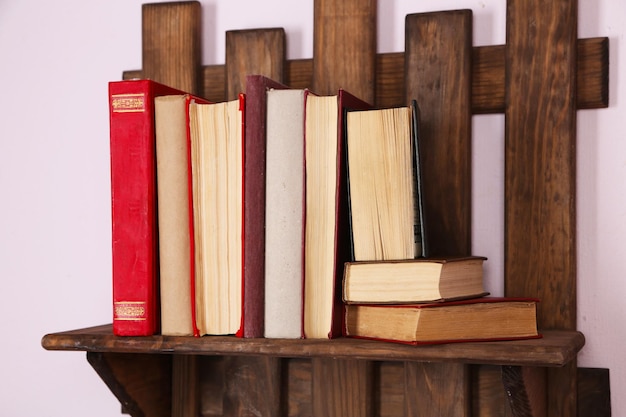 Wooden shelf with books on wall closeup