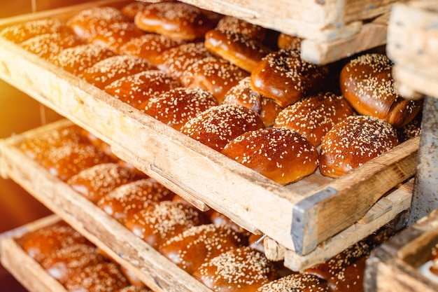 Wooden shelves with fresh pastries in a bakery. Sesame Buns.