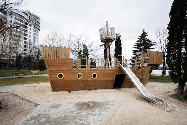 Wooden ship and slide in children playground in city