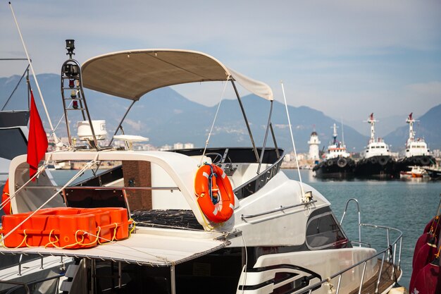 Wooden side of the boat, painted white and brown, with a orange  lifebuoys.