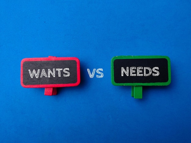 WANTS VS NEEDSと書かれた木製のサインボード