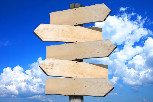 Wooden signpost with five clear arrows sky with clouds in background