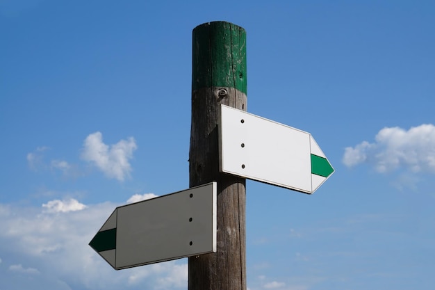 Wooden signpost with two arrows and sky in background