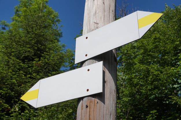 Wooden signpost with two white and yellow arrows