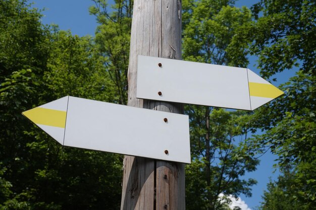 Photo wooden signpost with two white and yellow arrows