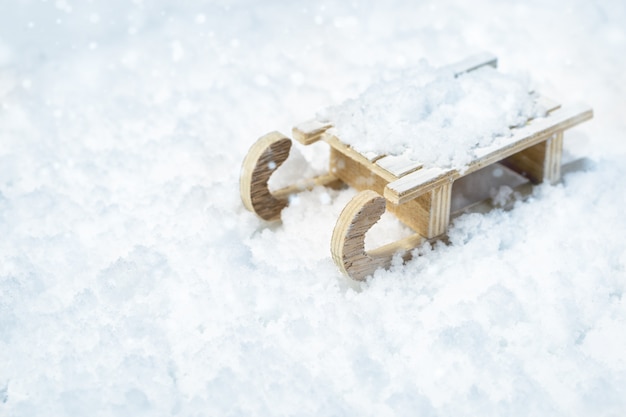 Foto slitta di legno su neve vaga con luce, messa a fuoco selettiva