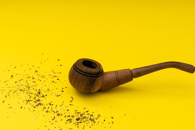 Деревянная курительная трубка с табаком на желтом фоне вредит курению