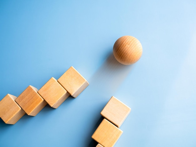 Wooden sphere rolling leading at front following with wood cube blocks on blue background Leadership business success unique difference challenge and motivation concepts