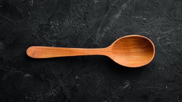 A wooden spoon on a black background Top view Free space for your text