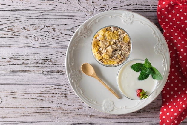 Wooden spoon, bowl of yogurt and bowl of oatmeal in bowl on wooden table