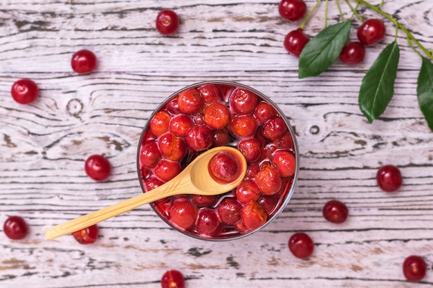 Cucchiaio di legno in una tazza di marmellata di ciliegie su un tavolo di legno