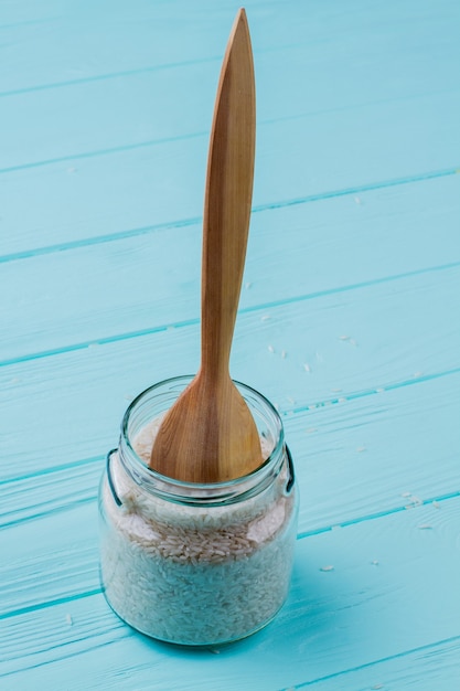 Photo wooden spoon dug in can of rice. wooden table on background.