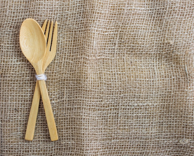 Photo wooden of spoon and fork set on sackcloth background.