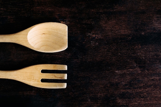 Foto cucchiaio di legno e forchetta sul tavolo. una forchetta e un cucchiaio di legno si trovano su un tavolo di legno marrone. accessori per la cucina. spazio per il testo