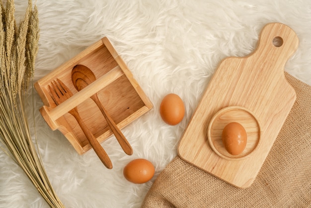 Foto cucchiaio e forchetta di legno in cestino di legno con l'uovo sul bordo di legno