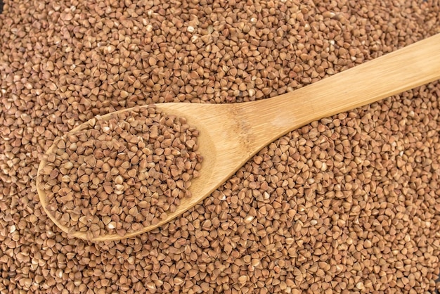 Wooden spoon in a heap of buckwheat Healthy food and lifestyle