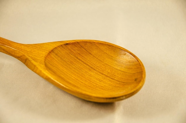 A wooden spoon is on a white cloth with a wooden handle.