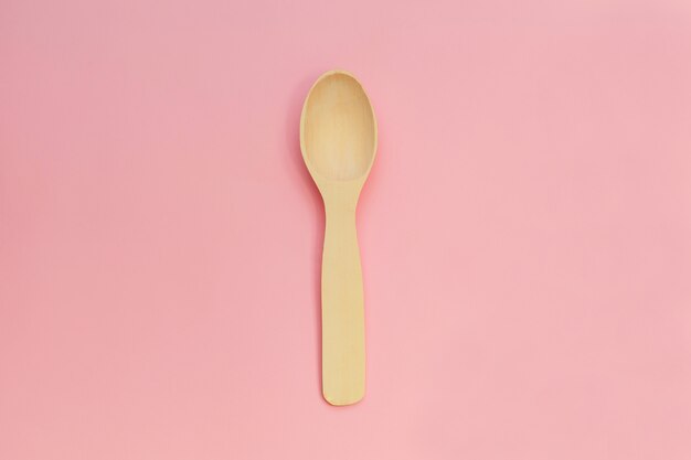 Wooden spoon isolated on pink background