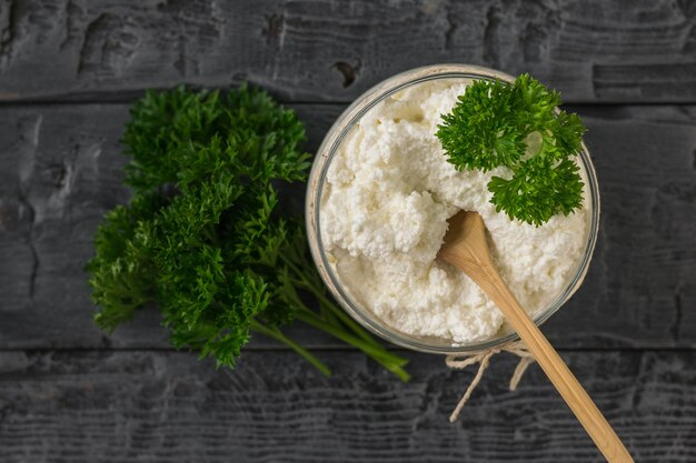 Wooden spoon in a jar with fresh cottage cheese on a wooden table. The concept of a healthy diet. Curd cream. The view from the top.