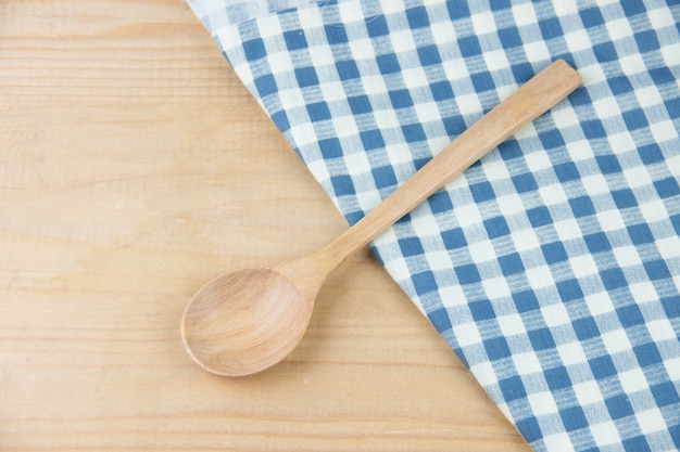 Wooden spoon on napkin blue and white plaid on wooden table